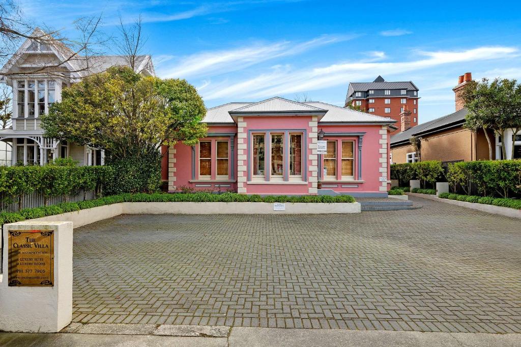 une maison rose avec une allée en briques devant elle dans l'établissement The Classic Villa, à Christchurch