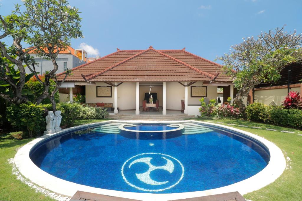 een zwembad in de tuin van een huis met een huis bij Heliconia Villa in Seminyak