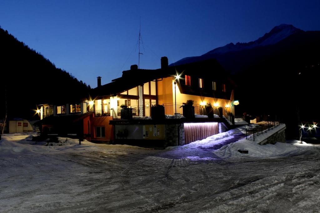 a house in the snow at night with lights at Chalet Presanella in Temù