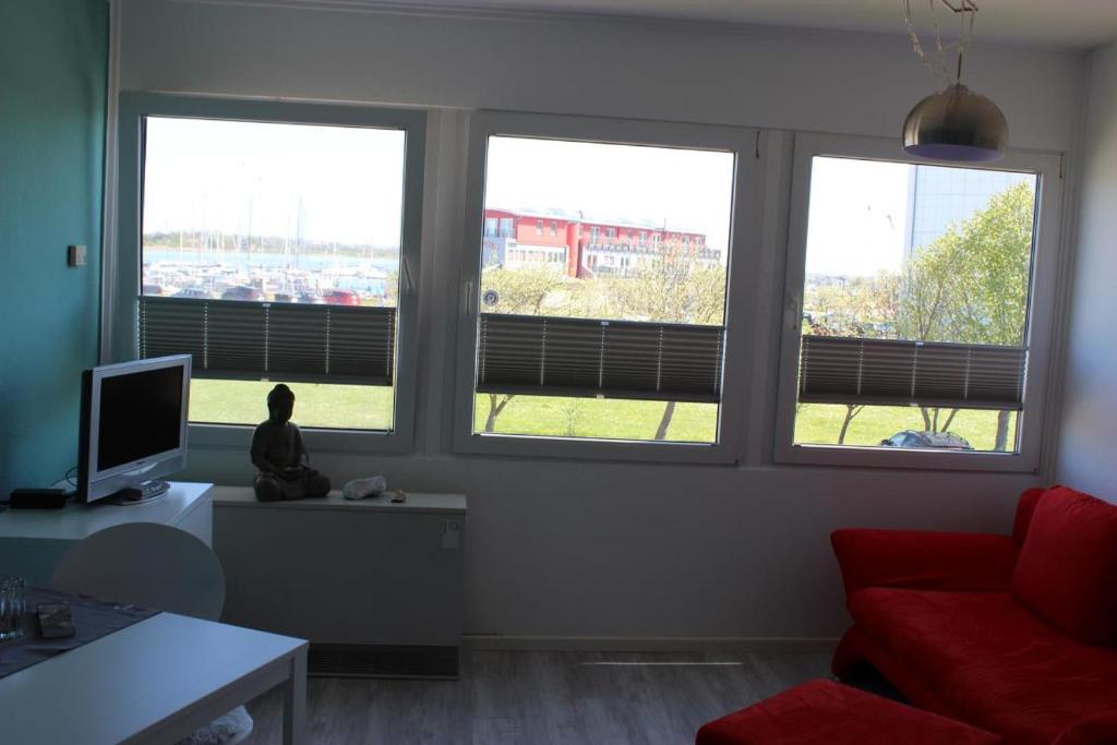 フェーマルンにあるFerienwohnung am Yachthafenのリビングルーム(窓3つ、赤いソファ付)