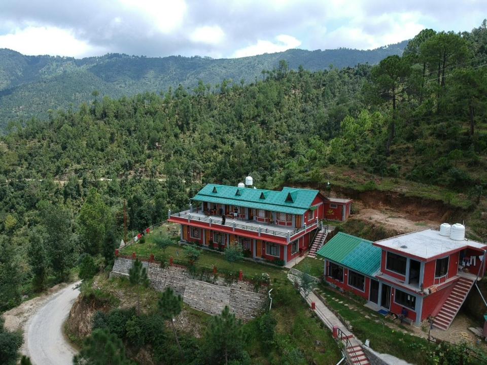 a large house with a green roof on a hill at Oak Essence in Mukteshwar