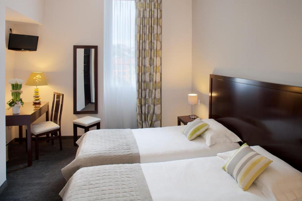 a hotel room with two beds and two lamps at Hôtel Relais Acropolis in Nice