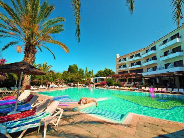 a large swimming pool with chairs and a hotel at 2 bedroom townhouse, close to Paphos harbour, use of onsite facilities in Paphos