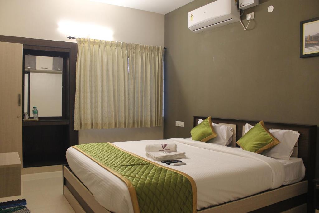 a bedroom with a large bed with green pillows at Viswa Residency by Azalea in Madurai