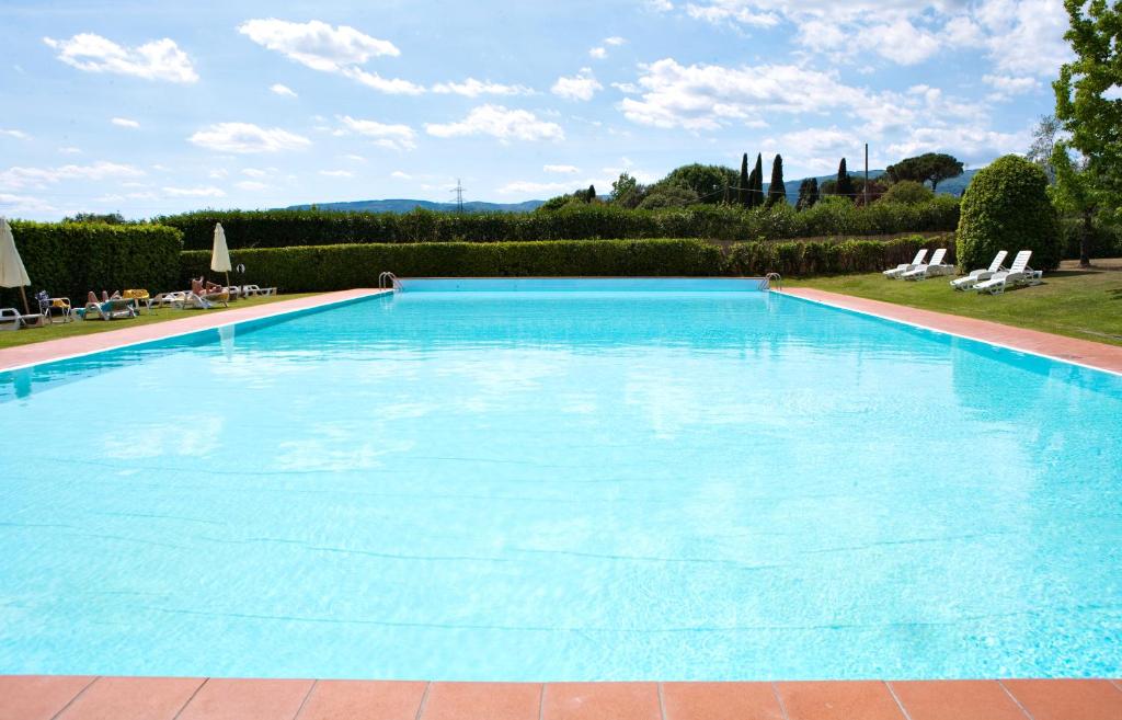 a large blue swimming pool with chairs and trees at Hotel Villa Cappugi in Pistoia