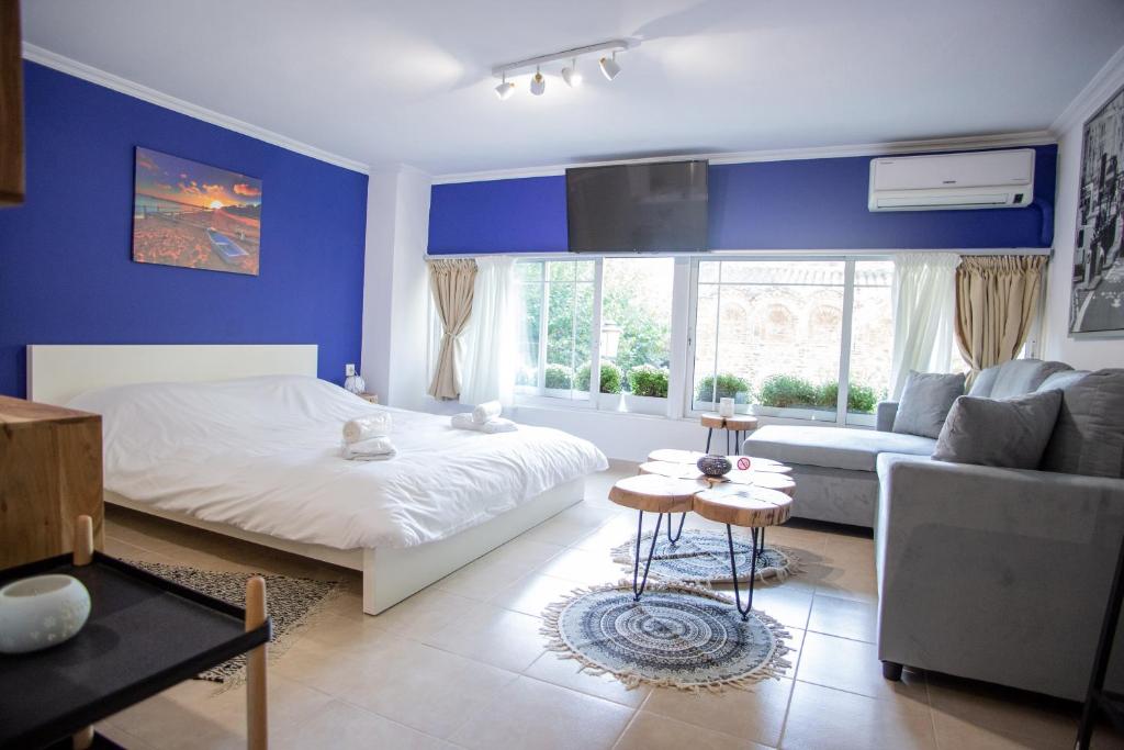 sypialnia z niebieskimi ścianami, łóżkiem i kanapą w obiekcie Thessaloniki Center Small Studio Apartment w Salonikach