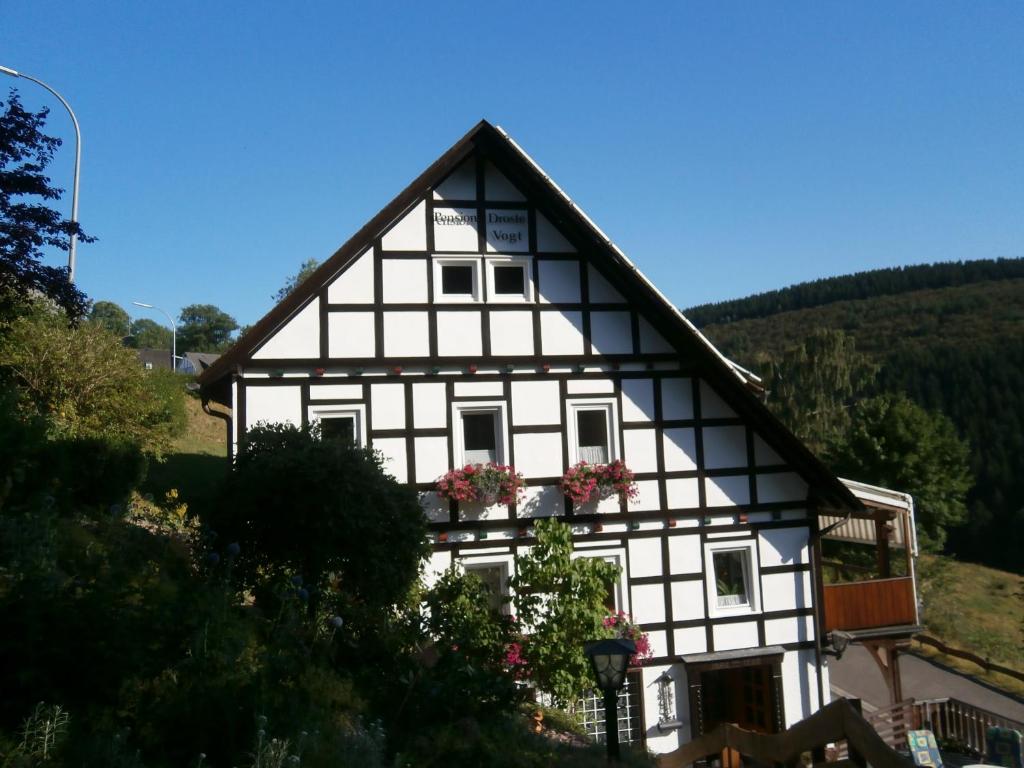 Una casa blanca y negra con flores. en Pension Droste- Vogt, en Schmallenberg