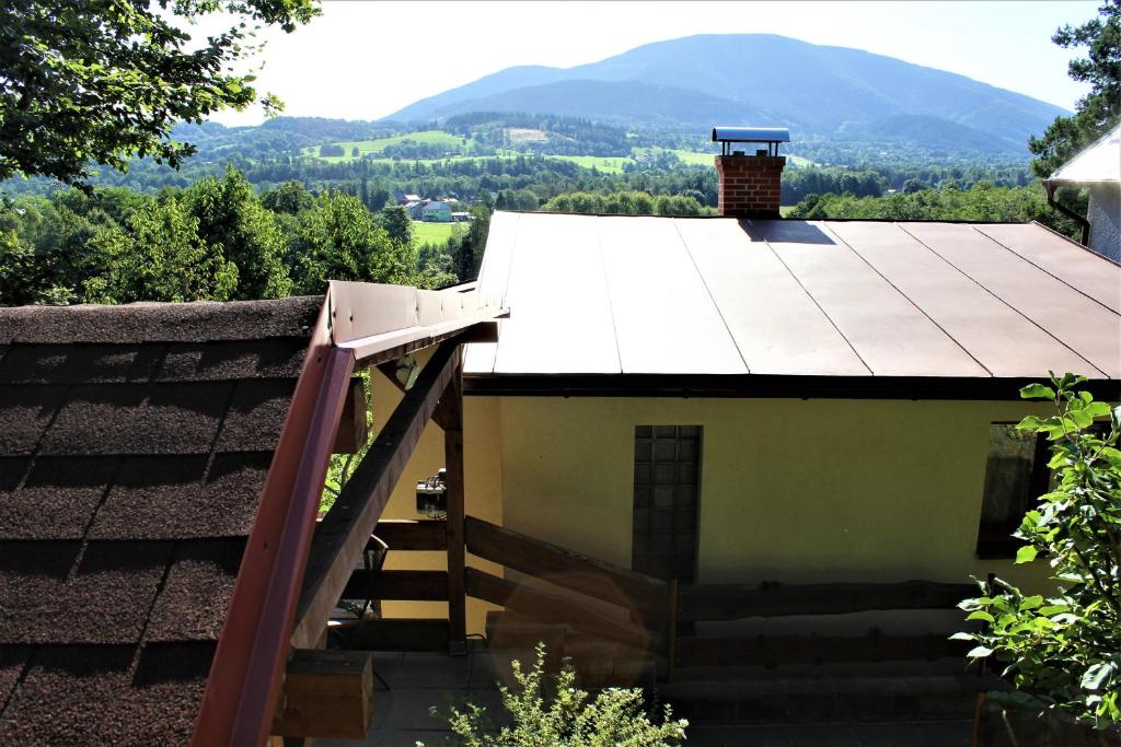 a house with a roof with a staircase and mountains in the background at Babiččin Vejminek in Čeladná