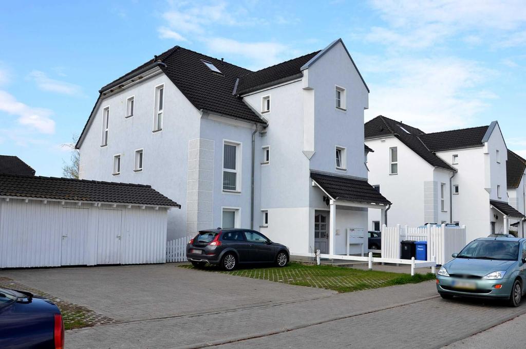 una gran casa blanca con coches aparcados en un aparcamiento en Ferienwohnung Sandpiper, en Ostseebad Nienhagen