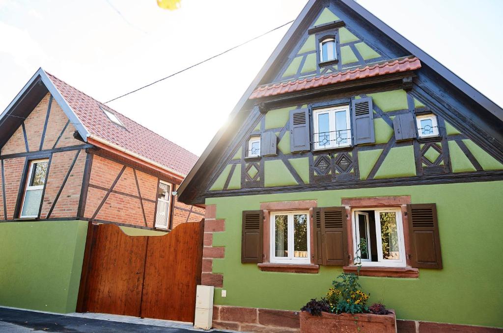 a green and brown house with a wooden fence at La Forge in Ringendorf