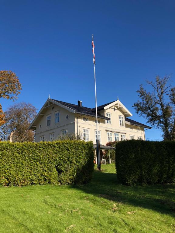 ein großes weißes Haus mit amerikanischer Flagge auf einer Stange in der Unterkunft Gjedsjø Gaard in Ski