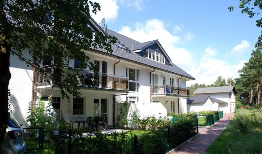 una casa blanca con una valla delante en Ferienwohnung Strandrose, en Thiessow