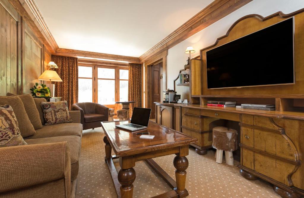 a living room with a television and a laptop on a table at Hôtel Les Barmes De l'Ours in Val-d'Isère