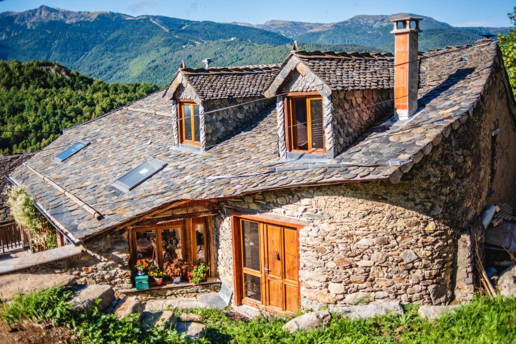 a stone house in the mountains with mountains in the background at The Dragon Barn - Grenier in Ascou