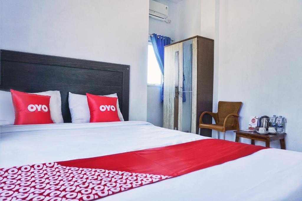 um quarto com uma cama grande e almofadas vermelhas em SUPER OYO 1565 Hotel Homiko em Pacitan