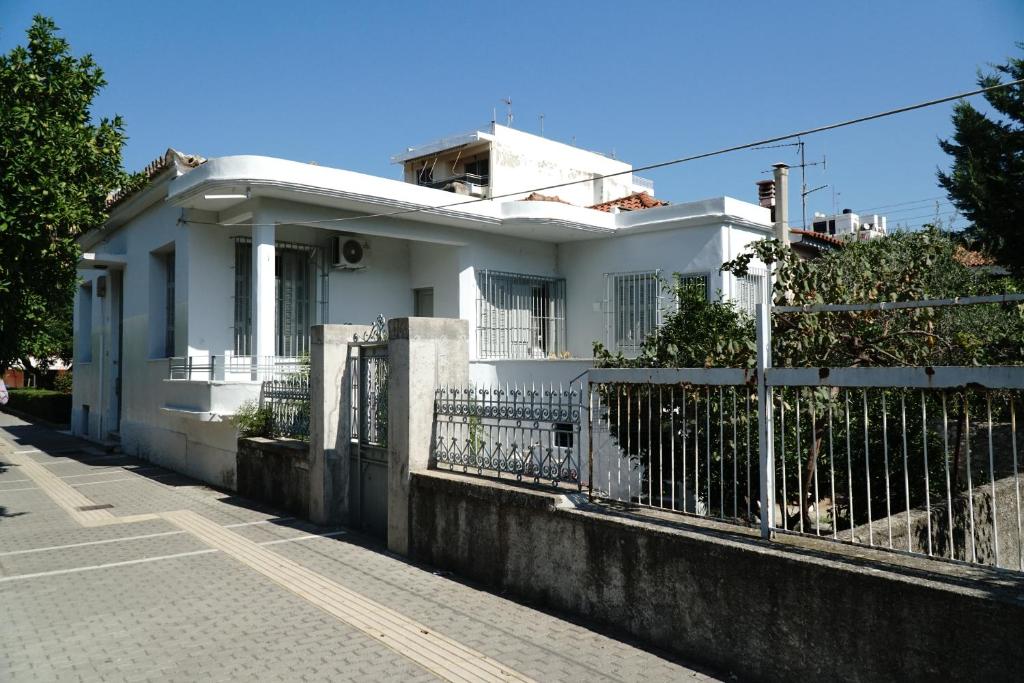 ein weißes Haus mit einem Zaun neben einer Straße in der Unterkunft Aggelis Traditional Appartment in Sparta