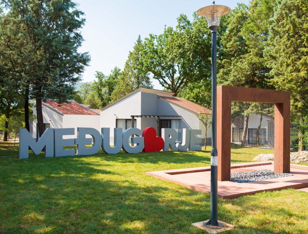 un cartel en el césped frente a un edificio en FoRest Međugorje, en Međugorje