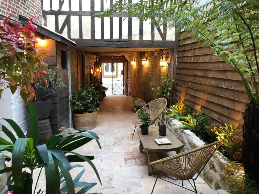 een patio met stoelen, een tafel en planten bij LE PATIO / les suites romantiques du grenier à sel in Honfleur