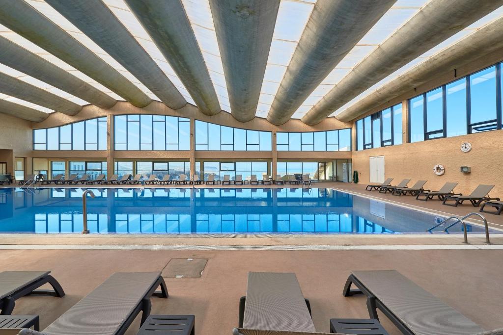 una gran piscina con mesas y sillas en un edificio en Hotel Golf Mar en Maceira
