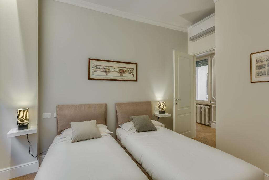 2 łóżka w pokoju z białymi ścianami w obiekcie Sophisticated Home we Florencji