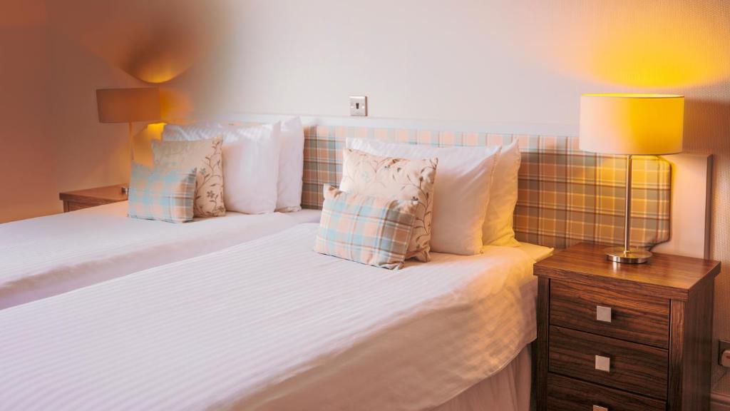 a bedroom with a bed with white sheets and pillows at The Pines Hotel in Swanage
