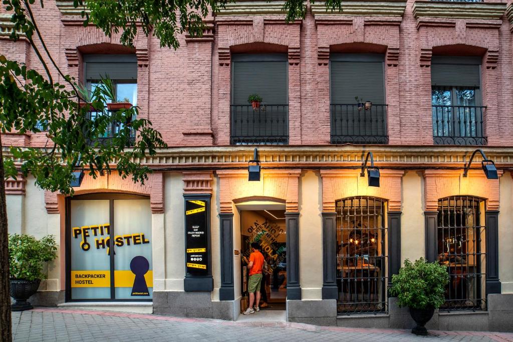 een winkel voor een bakstenen gebouw met mensen in het raam bij Petit Hostel La Latina in Madrid