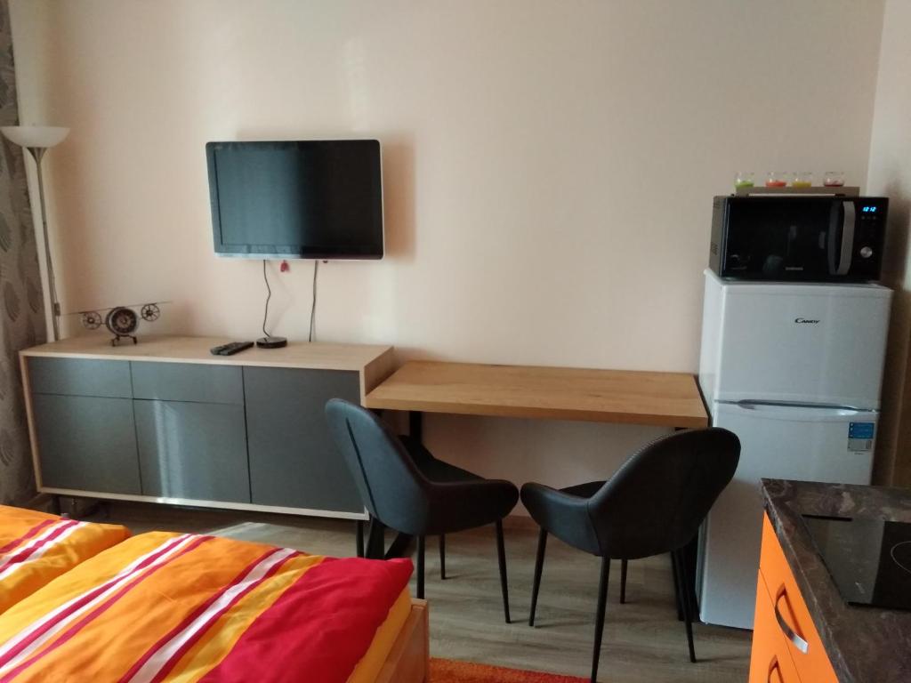 a room with a desk with two chairs and a television at Apartmán ALEX in Poprad