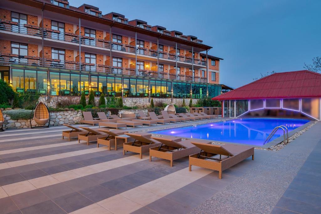 um hotel com piscina e cadeiras e um edifício em Savaneti Eco Hotel em Telavi