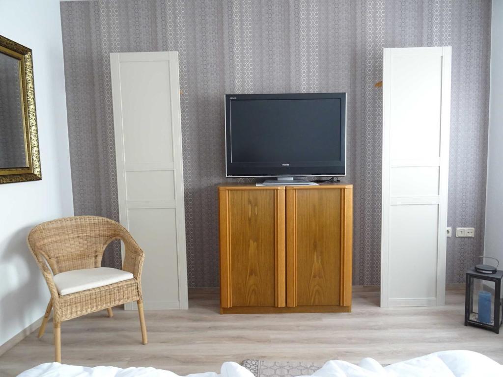 een woonkamer met een televisie en een stoel bij Ferienwohnungen "Kajüte Leer", 15199 in Leer