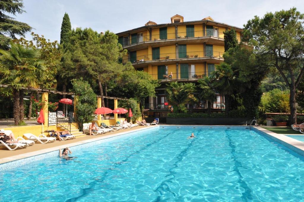 a swimming pool in front of a hotel at Hotel Palme & Suite in Garda