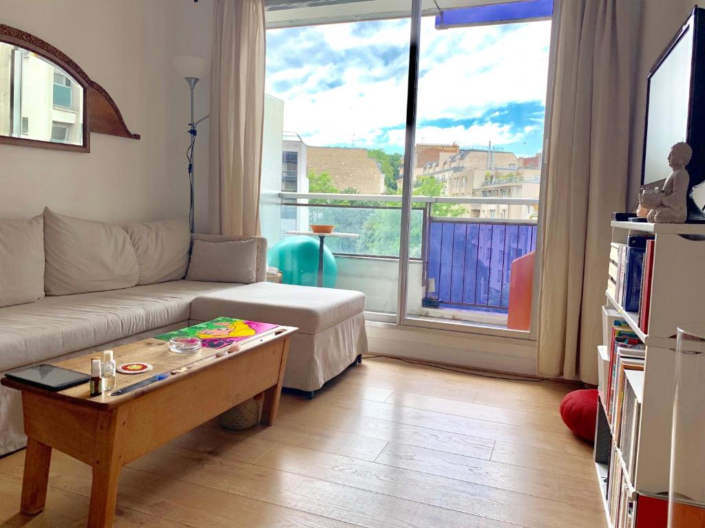 ein Wohnzimmer mit einem Sofa und einem Couchtisch in der Unterkunft Jolie chambre privée à Paris dans appart de 75m2 in Paris