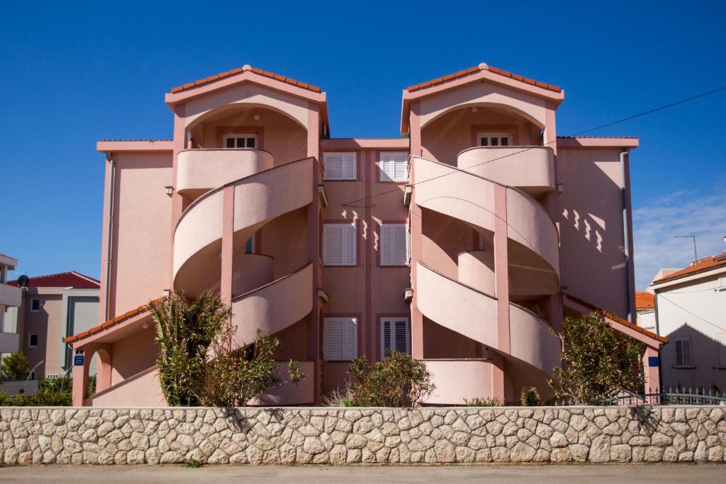 a building with two balconies on top of a wall at Pink House Apartments in Novalja