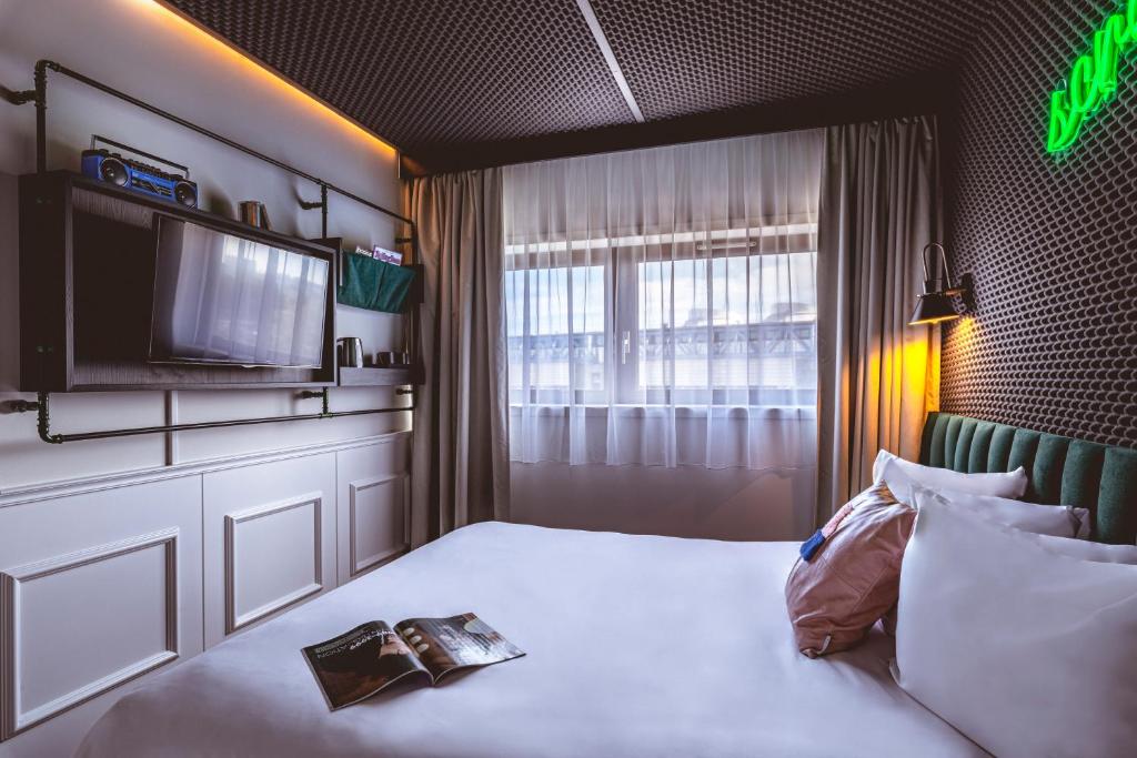 a hotel room with a bed with a tv on it at The ReMIX Hotel in Paris