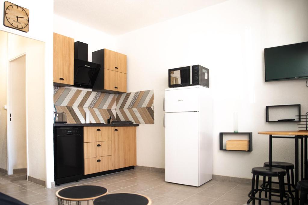 een keuken met een koelkast en een tafel bij le studio du Grazel in Gruissan