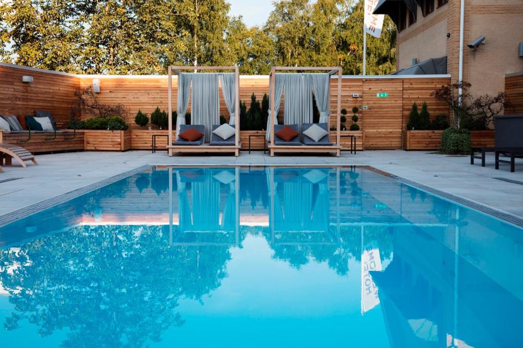 uma piscina com duas cadeiras em frente a uma cerca de madeira em Welcome Hotel Barkarby em Järfälla