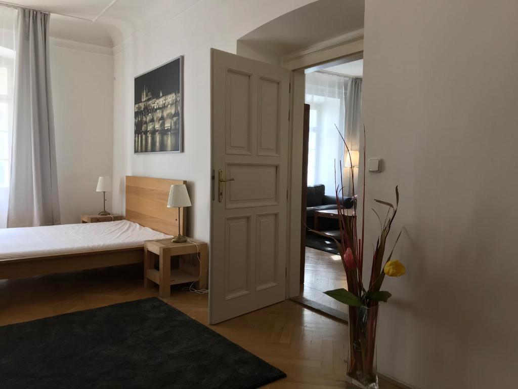 Charles Bridge Apartments في براغ: غرفة نوم مع سرير و مزهرية مع الزهور