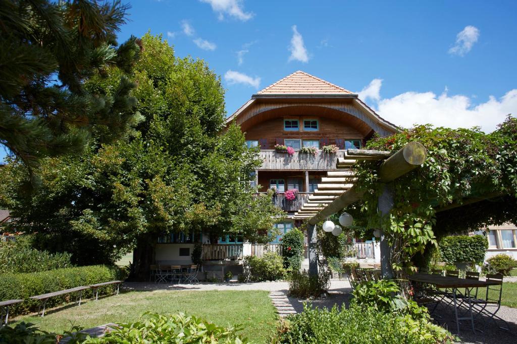 ein großes Haus mit einem Balkon und Bäumen in der Unterkunft Bio Garni Möschberg in Grosshochstetten