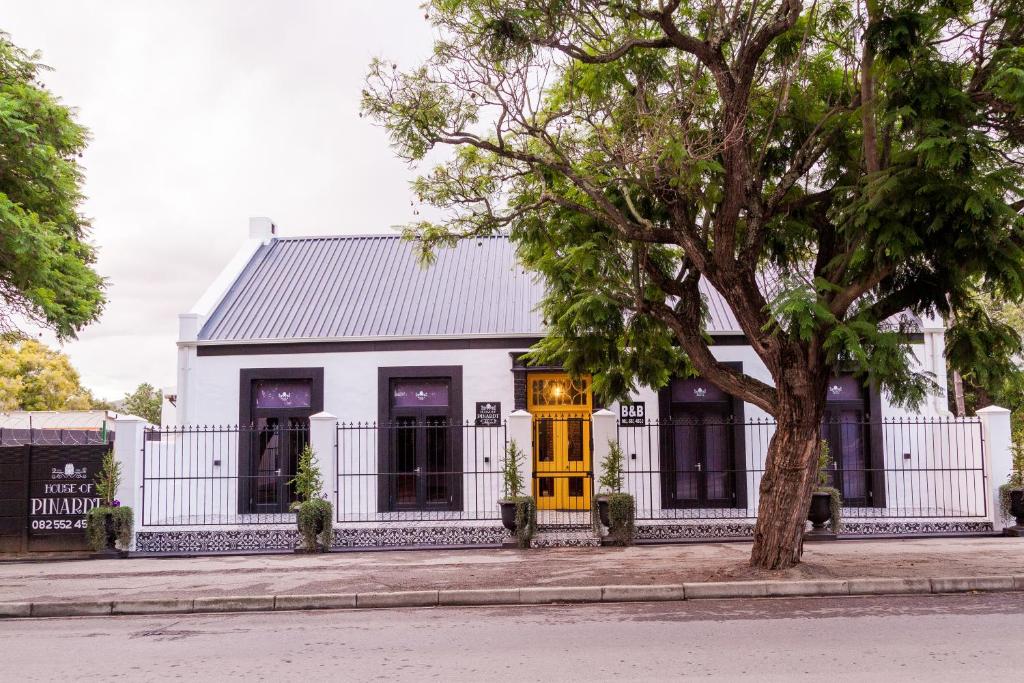 una casa blanca con una puerta amarilla y un árbol en House of Pinardt, en Robertson