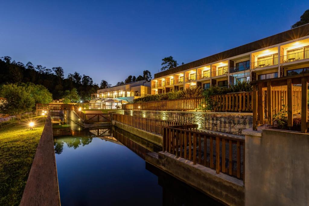 a row of buildings next to a river at night at Hotel Rural Vale Do Rio in Oliveira de Azemeis