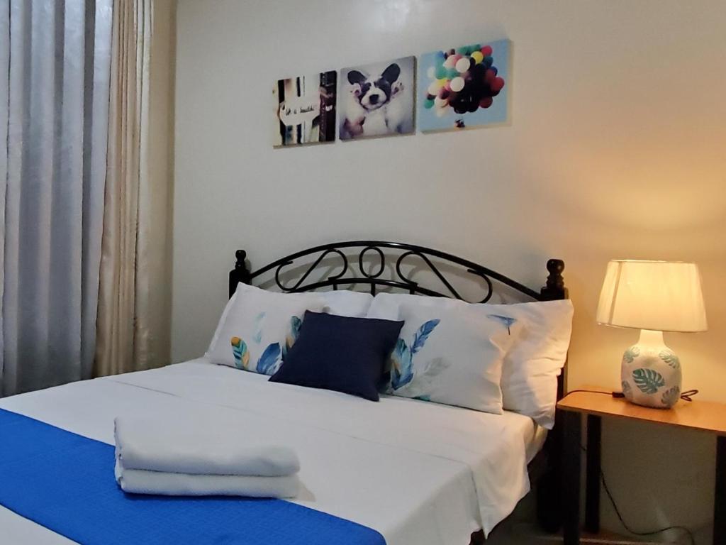 Schlafzimmer mit einem Bett mit weißer Bettwäsche und blauen Kissen in der Unterkunft Jen's Paranaque City Apartment in Manila