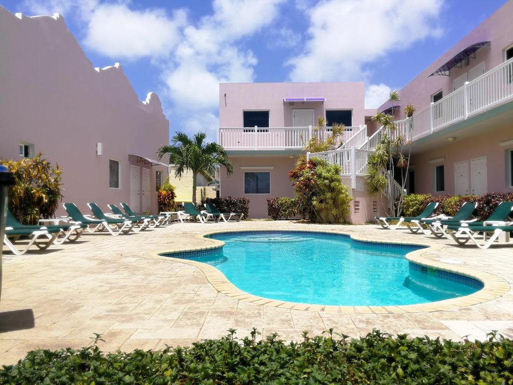 a swimming pool in front of a building with lounge chairs at Agua Clara Eco Suites in Oranjestad