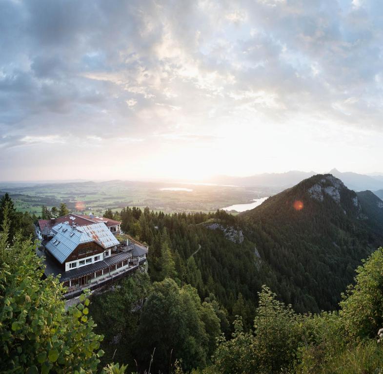 a building on the side of a mountain with trees at Boutiquehotel Blaue Burg Falkenstein in Pfronten