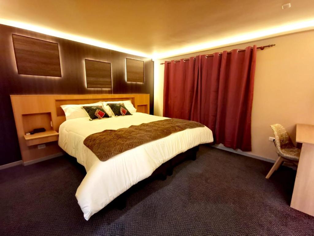 a bedroom with a large bed and a red curtain at Hotel Mont Suite-Mte. Aguila in Cabrero