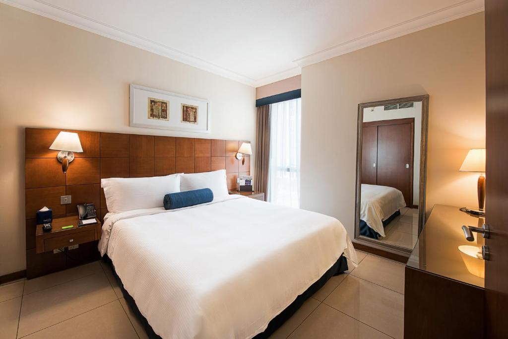 a hotel room with a large bed and a mirror at Al Rawda Arjaan by Rotana, Abu Dhabi in Abu Dhabi