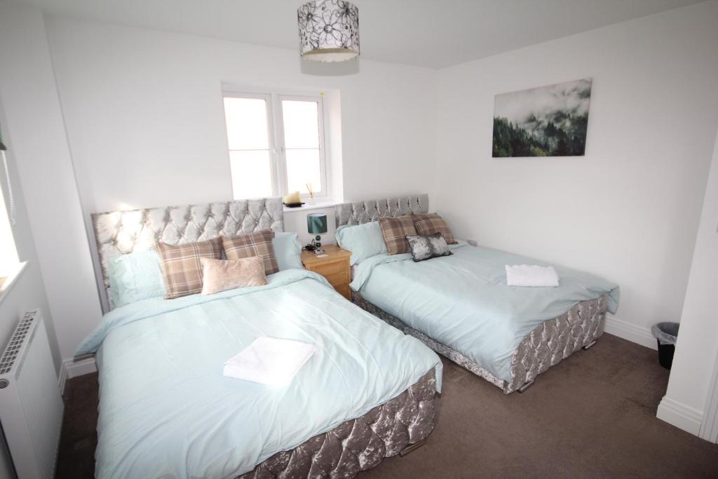 twee bedden in een kamer met witte muren bij The Langley House in Slough