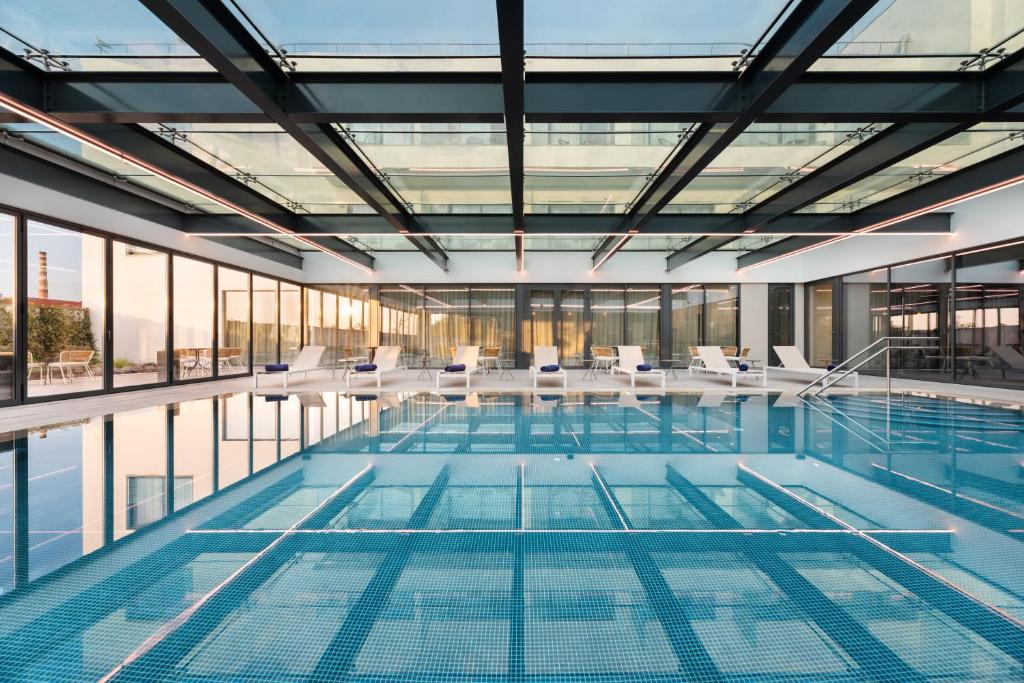 a swimming pool with chairs and windows in a building at Eurostars Matosinhos in Matosinhos
