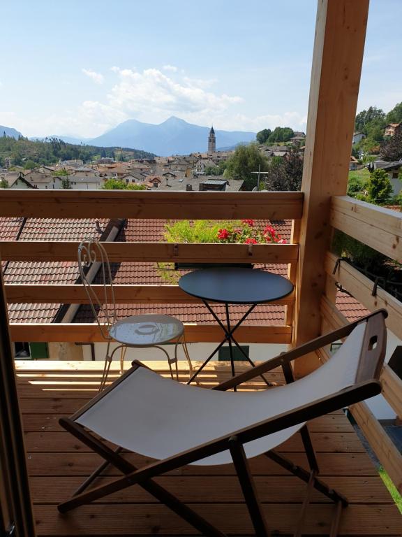 una silla y una mesa en un balcón con vistas en ANESI appartamenti, en Baselga di Pinè