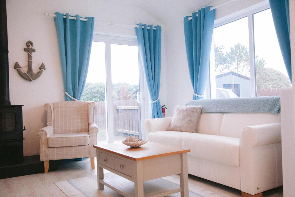 sala de estar con sofá blanco y cortinas azules en Sandville Chalet Portnoo, en Portnoo