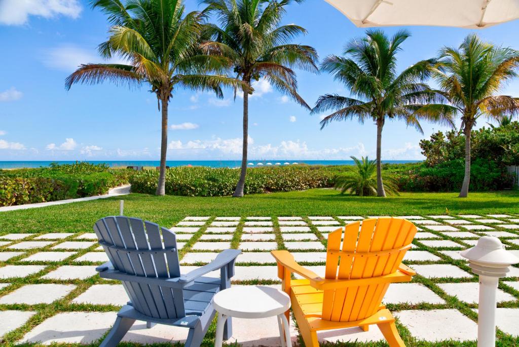 2 chaises assises sur une terrasse avec des palmiers dans l'établissement Prestige Hotel Vero Beach, à Vero Beach