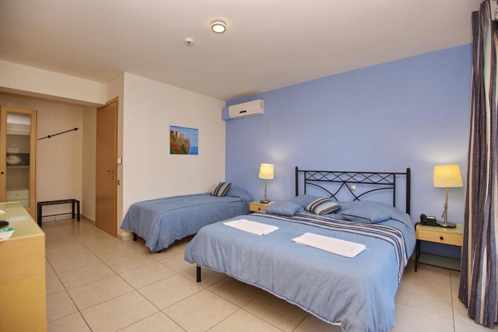 a bedroom with two beds with blue comforters at 4epoches in Steni Vala Alonissos